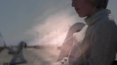 Kız iskelede oturuyor, kamera kayıyor ve pazarlama için dalgalı ışık örtüsü ile yüzünü gösteriyor. Çocuk, yaşam tarzı, minimalist, fotoğrafçılık, açık hava, dinginlik, deniz kenarı