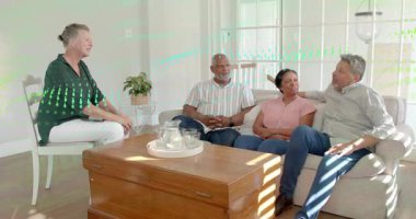 Ev sahibi öne eğilip el kol hareketi yapıyor. Oturma odasında tabletle önde gelen sağlık konuşmaları, kafa sallamalar. Konuşma, röportaj, tartışma, gün ışığı, çizgili, pencere, perdeler