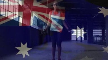 Kadın bileklerini çeviriyor, halat sallıyor ve spor salonuna koşuyor. Bu arada Amerikan bayrağı çerçeveyi örtüyor. Atlama, atletik, kardiyo, endüstriyel, depo, doğal ışık, yan keyif