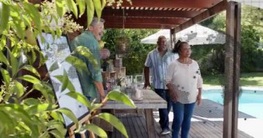 Grup hazırlık masasındaki kadın etkinlikler için hareketli konfetiyle alkışlamaya neden oluyor. Arka bahçe, havuz başı, pergola, balonlar, kutlama, şenlik, mutluluk