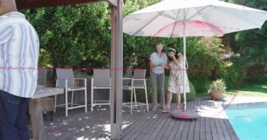 Gözleri bağlı bir kadın, telefonlu bir adam havuz başında sürpriz bir kutlama yaparken rehberlik ediyor. Arka bahçe, havuz, kutlama, açık hava, birliktelik, arkadaşlar, aile