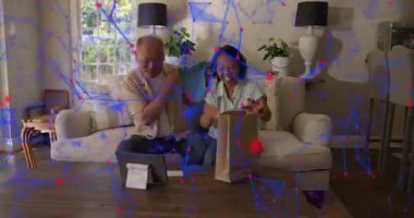 Olgun çift koltukta çantasına uzanıyor, tablet için mavi nesneyi gösteriyor, ağ geribildirim için, üstüste biniyor. Partnerler, ev, etkileşim, giysi, kumaş, dijital, minimalist