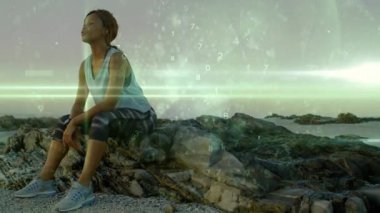 Kayanın üzerinde oturan, saati kontrol eden, yere yığılmış, gözleri ovalayan yeşil bantlı bir kadın. Kıyı, kıyı şeridi, çıkıntı, ufuk, açık hava, dalgın, sakin