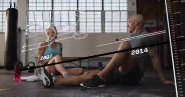 Eğitimli bir çift spor paspasının üzerinde oturup, spor salonunun hızını gösteriyor ve çak bir beşlik çakıyor. Spor, partnerler, sohbet, dostluk, gün ışığı, minimalist, modern