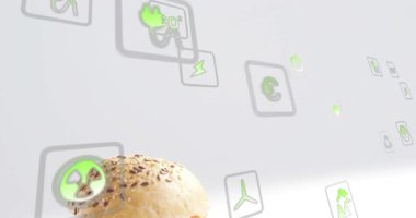 Top bun ortaya çıkıyor, kamera kayıyor, eko-ikonlar yüzerken çizburgeri ortaya çıkarıyor, yeşili gösteriyor. Sandviç, köfte, peynir, marul, domates, parlak, minimalist