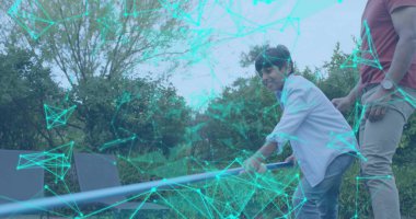 Bahçede metal kiriş tutan gülümseyen çocuk, babamın paslı tişörtü, kotu, deniz mavisi kaplaması, fotokopi alanı. Oyun alanı, açık hava, yeşillik, aile, ebeveyn, bağ, bahçe