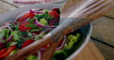 Salata kasesinde parlayan haritamsı kaplama, besin değeri gösterilirken sunucular kayıyor. Marul, domates, fesleğen, zeytin, tabak, ahşap, kesme tahtası