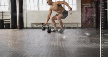 Adam kettlebell 'e uzanıyor, pedlerin üzerinde dengede duruyor ve HUD' nin fitness verilerini kapladığı sırada sallanıyor. Spor salonu, ağırlık, atlet, antrenman, güç, hareket, denge