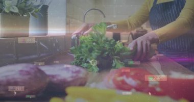 Şifalı otlara uzanan, musluğu çeviren ve şeffaf UI rozetleri yüzerken yemek pişirmek için durulanan bir kadın. Mutfak, maydanoz, yeşillik, çamaşır, lavabo, tezgah, önlük.