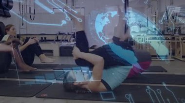 Mavi tanklı kadın çekirdek taklalarına pilates çekirdek dayanıklılığı için kıvrılarak başlıyor. Küre senkronizasyonu. Fitness, grup, paspas, stüdyo, reformcu, senkronize, takım çalışması