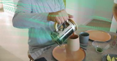 Fransız presi kaldıran, bej bardağa kahve dolduran, sonra da gri bardak, paylaşılan kahvaltıyı hazırlayan bir adam. Mutfak, ikili, gündelik, modern, tezgah, sohbet, sabah