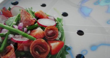 Kamera sağa doğru kayıyor, salata kaplamalı. Mönü tasarım vitrininde rosetler ve dokular ortaya çıkıyor. Yakın plan, yeşillik, roka, turp, çilek, prosciutto, balzamik