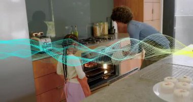 Anne-kız fırını açıyor, eldiven tepsisi alıyor, kekleri soğutma rafına yerleştiriyor, noktalı kaplama yapıyor. Mutfak, pişirme, ebeveyn, çocuk, sıcaklık, birlikte, aydınlık