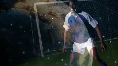 Erkek kaleci gol kaydetmek için sürekli yer değiştiriyor, tepki veriyor ve dalıyor. Dünya gol üzerine genişliyor. Gardiyan, oyuncu, futbol, çim, açık hava, gece, ışıklar