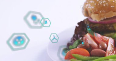 Sürüklenen deniz mavisi büyüsü simgeleri kamera görüntülemesini başlatıyor, menü için kaplanmış hamburger ve patates kızartmasını ortaya çıkarıyor. Sandviç, köfte, susam, domates, yeşiller, stüdyo, Highkey