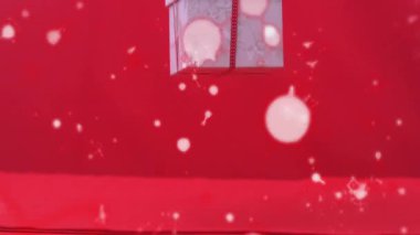 Mermer hediye kutusu yukarıdan düşüyor, dönüyor ve sallanıyor, kırmızı sette sergilenmek üzere ayarlanıyor. Hediye, şablon, kurdele, yay, bokeh, parıltı, stüdyo