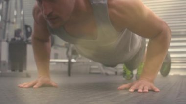 Adam tahtaya başlıyor, aşağı iniyor ve bastırıyor spor olsun diye halterin yanında kauçuk minder üzerinde şınav çekiyor. Spor salonu, ağırlık, antrenman, güç, vücut ağırlığı, odaklanma, mercek.