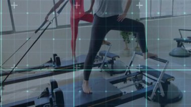 Reformcuların üzerine basan ve pilates için halat tutan iki kadın, şebeke duruşları örtüyor. İkili, fitness, stüdyo, ekipman, direniş, kayışlar, ortaklar