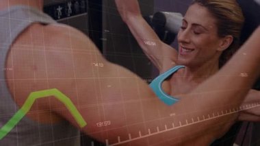 Kadın ellerini makineye koyup saplarını çekerken erkek fark ediyor, yeşil grafik izleme kondisyonu. Ekipman, spor salonu, antrenman, ikili, koç, atlet, güç