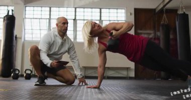 Koç tabletçi kadın, KB 'yi yan baskı yaparak spor salonunun şifresini belirsizleştiriyor. Kettlebell, kuvvet, antrenör, form, çekirdek, istikrar, odaklanma