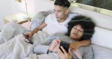 Telefonu yürüten, yatakta koluna sarılan telefonu eğen, eğlenceli teknoloji içeriğini paylaşan bir adam. Çift, samimiyet, romantizm, rahat, sıcak, yatak odası, cihazlar