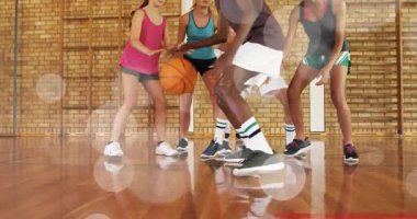 Okulun top sürücüsü top sektirme yapıyor, defans oyuncuları sayı yapmak için basket atışına itiraz ediyor. Top, çember, kort, sert ahşap, spor ayakkabılar, arka tahtası, takım arkadaşları