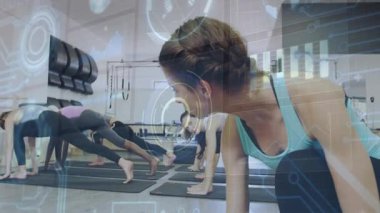 Teal kadın fitness sınıfını yönetiyor, şekil almak için kalasları yan tahtaya diziyor, H.U.D. görünür durumda. Eğitmen, grup, minderler, stüdyo, hareket, hizalama, üst üste