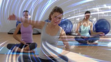 Lider kadın, takım çalışması için forma girerken kollarını kaldırıyor, grup yerine takım çalışmasını taklit ediyor. Yoga, minder, oturma, hizalama, denge, esneklik, stüdyo