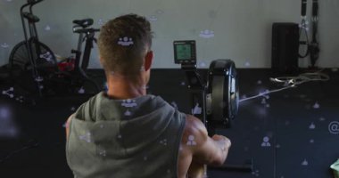Adam jimnastik salonunda spor yapmak için kürek çekiyor, sürüşe bacakları iterek başlıyor, simgeler ekranda yüzüyor. Ergometre, atlet, ev, kardiyo, dayanıklılık, odak, sinema
