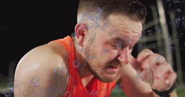 Yoğun eğitimden sonra iyileşen, terleyen ve öksüren bir adam aynı zamanda akıllı seğirmeyi izliyor. Sporcu, açık hava, gece, çim, projektör, iz sürücü, terleme