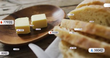 Başlangıçta rozetler görünür, sürüklenir, dilimlenmiş ekmek üzerinde kümelenir ve yemek gösteren iki tereyağı küpü. Kırsal, ahşap, somun, dilimler, tabak, bıçak, peçete