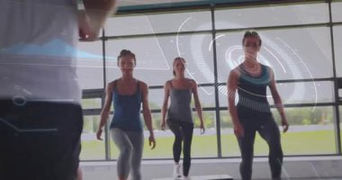 Eğitmen Demo 'yu izleyen üç kadın katılımcı fitness platformlarına basıyor, HUD rehberliği yapıyor. Spor, kadınlar, adım, kardiyo, stüdyo, gün ışığı, yeşil alan