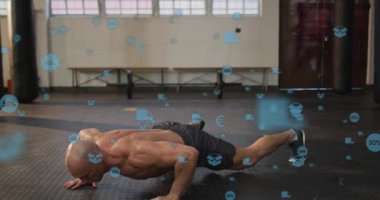 Erkek antrenör yukarı itiyor, diz çöküp gidiyor, yüzen mavi simgelerle fitness için şınav çekiyor. Sporcu, kaslı, spor salonu, stüdyo, bank, pencere, lastik