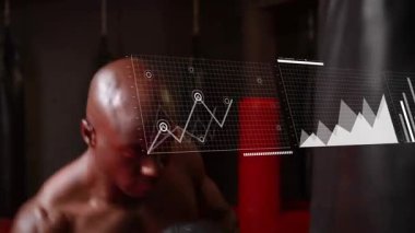 Erkek boksör veriye tepki veriyor, sporun haritasını çıkarırken torbaya yumruklar atıyor. Boks, spor salonu, atlet, eldivenler, yumruk, odaklanma, disiplin