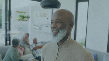 Aile sohbeti etrafında canlandırılmış sağlık ikonlarını tetiklerken oturma odasında gülümseyen kıdemli adam. Yaşlı, sıcak, birliktelik, toplanma, kanepe, kolye, ev