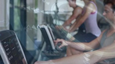 Sağ konsola dokunan ve HUD grafikleri ayarlarken kardiyo başlatılan kadın egzersizi. Spor salonu, fitness, bisiklet, koşu bantları, makineler, gün ışığı, modern