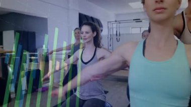 Beden eğitimi koçu ön kadının arkasında hareket ediyor. Çerçeveyi kapatırken kol hizasını düzeltiyor. Antrenman, grup, stüdyo, pilates, eğitmen, katılımcı, minder