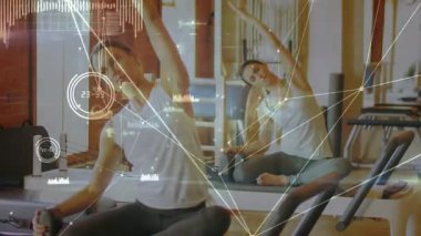 Bir kadın ıstakanın sapını sıkıca tutuyor, yan esneme hareketleri yapıyor, vücut geliştirme hareketlerini takip ediyor. Reformcu, pilates, ayna, denge, esneklik, stüdyo, kardiyo