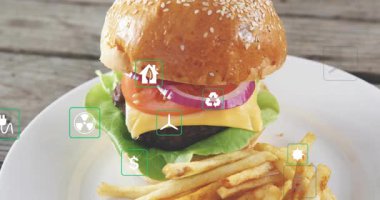 Yeşil simgeler susamlı burger kamerasının kenarlarından süzülüyor ve eko maliyetini gösteriyor. Sandviç, patates kızartması, masa üstü, kaplama, semboller, baharat, reklam.