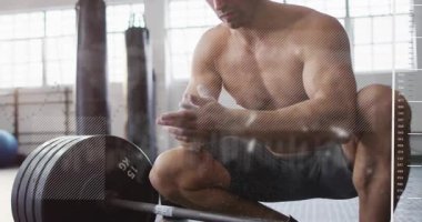 Erkek halterci tebeşir alıyor, ellerini ovuyor, halteri kavrıyor, kaldırma halterini HUD ile hazırlıyor. Sporcu, güç, odaklanma, eğitim, spor salonu, ekipman, toz