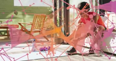 Eğilip, ayakkabıyı ayarlayan, egzersiz hazırlayan, örtülü çerçeveli minderi gösteren bir adam. Spor, ev, güneş ışığı, veranda, yoga, halterler, ayakkabılar.