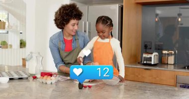 Annem sosyal medya için abur cubur hazırlayan bir kıza yardım ediyor, kalp sayacı güncellemesi yapıyor. Mutfak, aile, yemek pişirme, önlükler, ebeveyn, çocuk, işbirliği