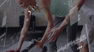 Kadın dambıllara uzanıyor ve antrenör pozisyonunu düzeltirken spor salonunu çekiyor. Güç, biçim, koçluk, bank, ağırlık, hareket, fitness