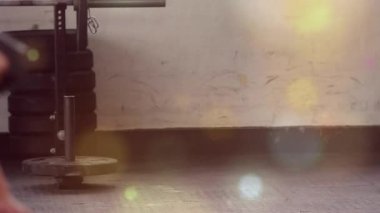 Adam dambılları sıkıca kavrayıp güç için kıvırırken, Bokeh da yumuşatma sahnesini örtüyor. Spor salonu, ağırlık, kıvrım, antrenman, odak, stüdyo, minimalist