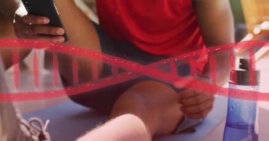 Oturan adam telefonu dinliyor, kırmızı sarmalları canlandırıyor ve spor olsun diye mavi şişe içiyor. Veranda, açık hava, canlı, sağIık, cihaz, egzersiz, güneş ışığı.