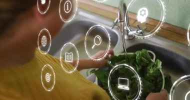 Lavabodaki kadın musluğu açıyor, yemek hazırlamak için yeşillikleri duruluyor ve simgeler ellerin üzerinde sürükleniyor. Mutfak, süzgeç, ıspanak, üretim, yıkama, kapama, samimiyet