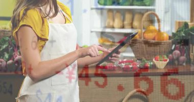 Tedarikçi tableti tıklatıyor ve üretim fiyatlarını güncellerken yarı saydam rakamların yüzmesine neden oluyor. Pazar, işçi, dokunmatik ekran, rakamlar, fiyatlandırma, meyve, sebze