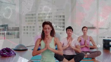 Eğitmen, yoga stüdyosunda üç kadını büyütüp sonra avuçlarını indiriyor, harita odak noktasını örtüyor. Trio, meditasyon, farkındalık, denge, gün ışığı, şehir manzarası, minderler