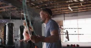 Garajdaki adam halata sarılıp zıplarken kadın kardiyo için ayna tutuyor. Partnerler, ikili, senkronize, kum torbaları, fitness, eğitim, endüstriyel