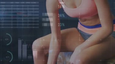 Büyülü dambıllara uzanan bir kadın spor salonunda kıvırcık saçlarını sergilerken HUD gücü takip ediyor. Halter, stüdyo, analitik, odaklanma, atletik, güç, eğitim